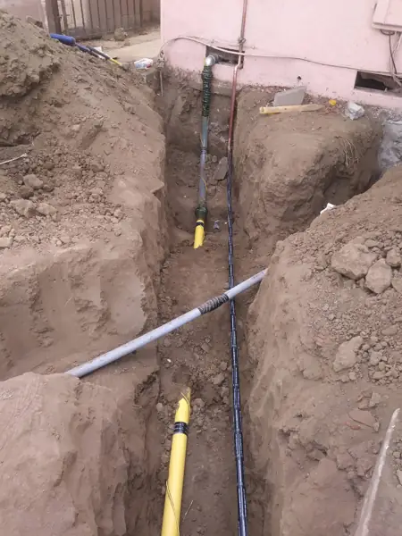 Open trench with a new yellow gas line and water line running to a house in Reseda