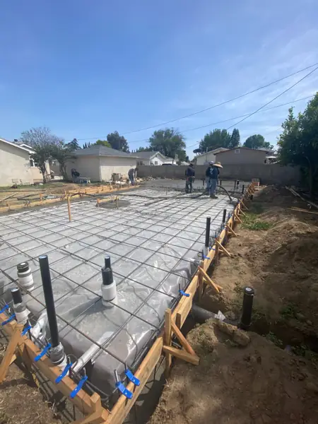 Plumbing stub-ups rising through rebar and vapor barrier before a concrete pour in Van Nuys