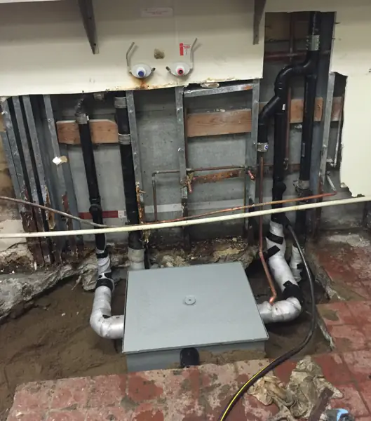Restaurant kitchen wall opened with new drain lines and a grease interceptor set in the floor in Tarzana