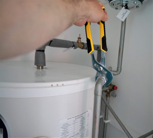 A person is using a pair of scissors to cut the water heater.