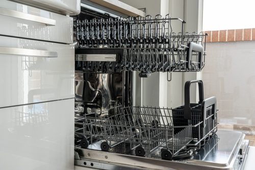 A dishwasher with the door open and dishes in it.